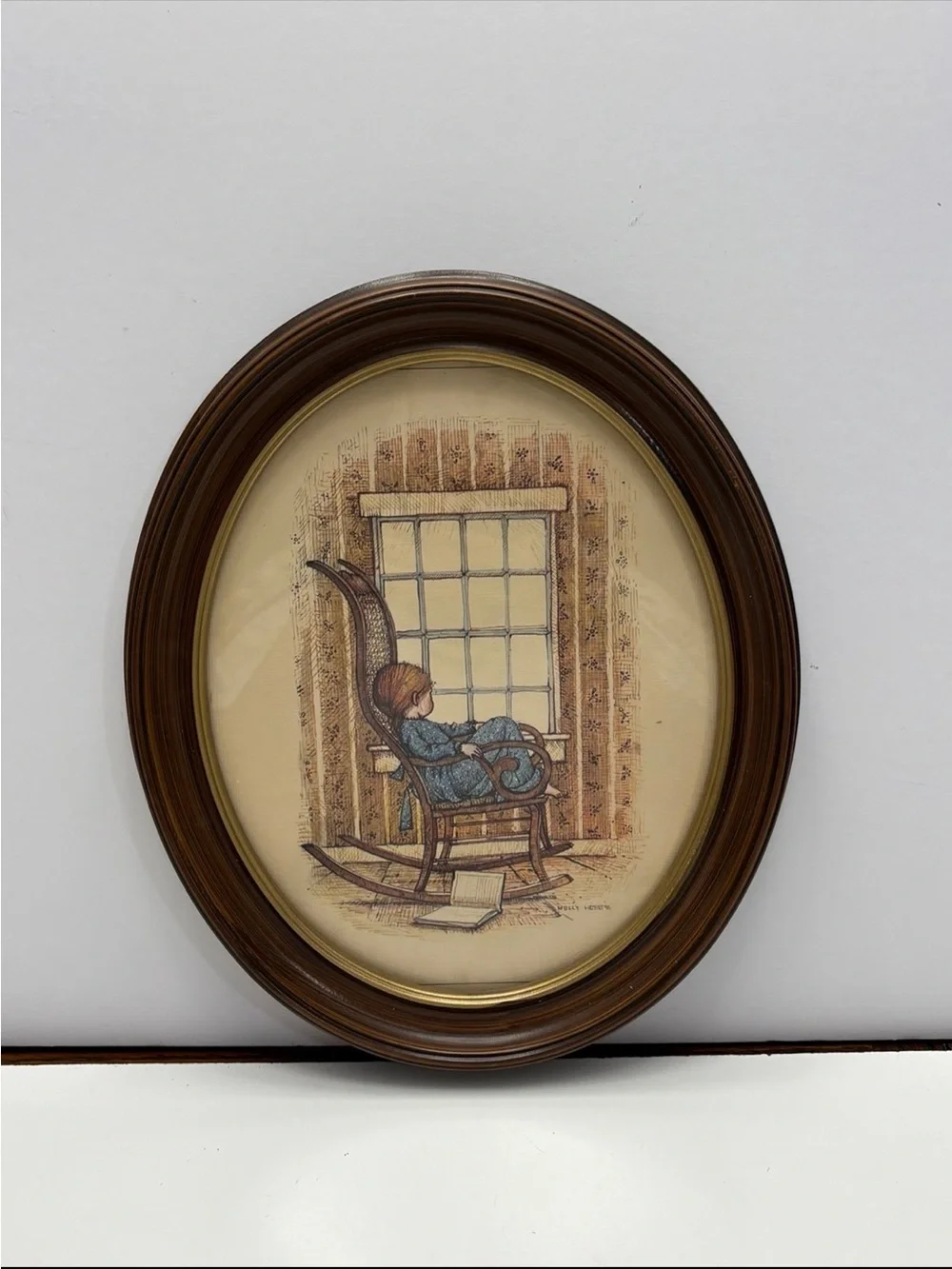 Vintage oval framed wall art piece featuring a girl in a rocking chair by a wind